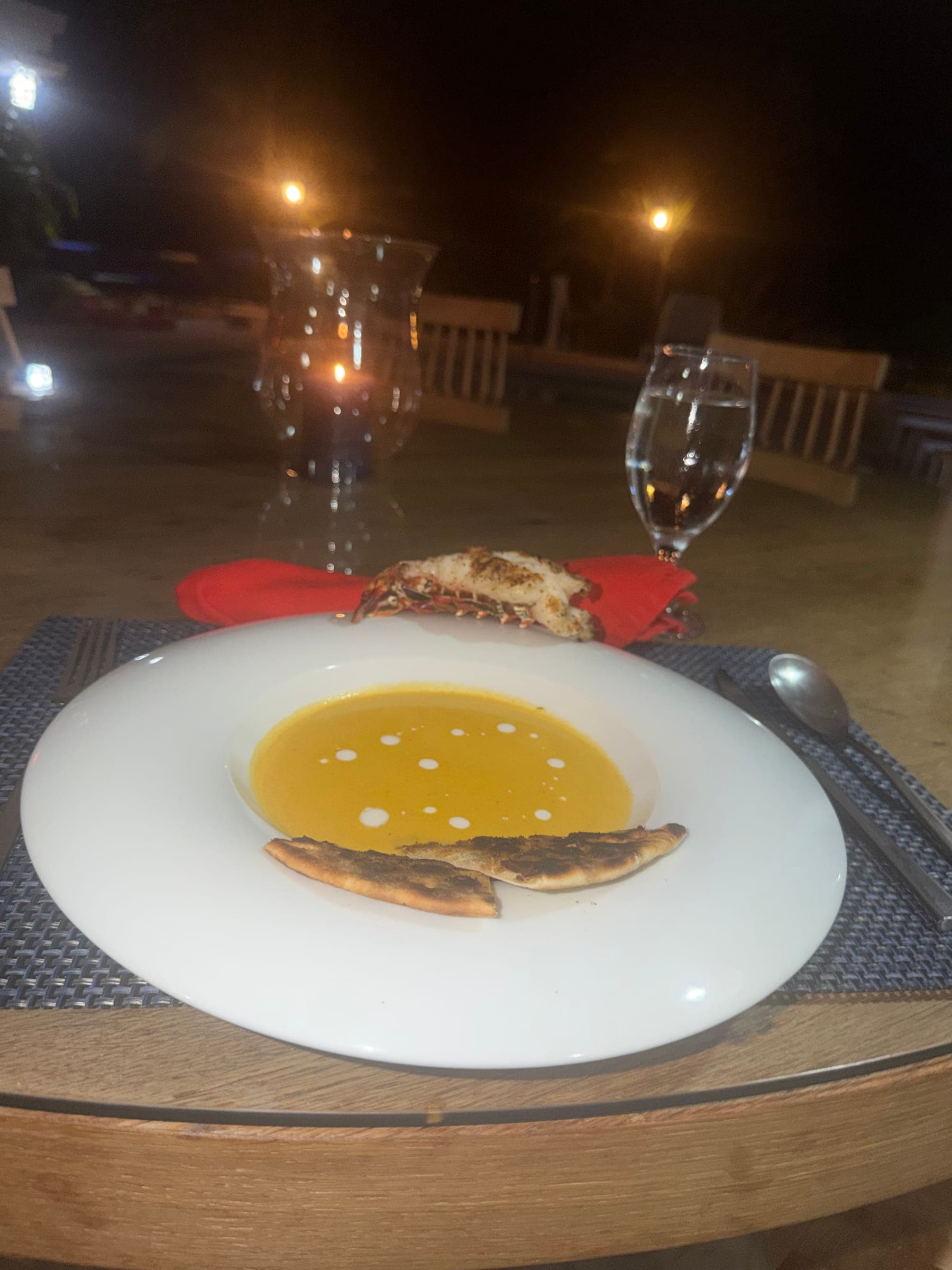 Candlelit dinner table with a soup course and wine glasses