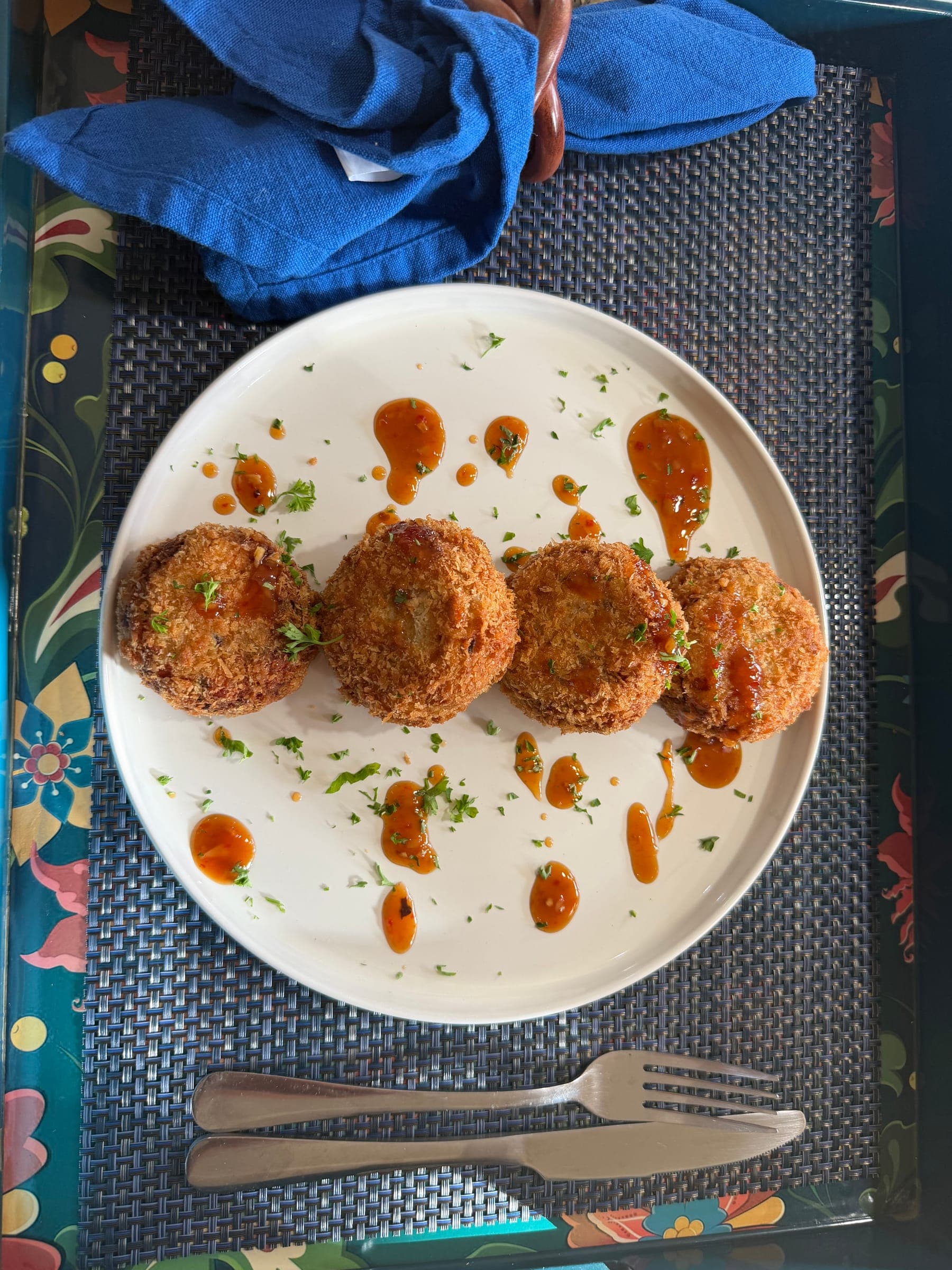 Golden fish cakes with dots of spicy sauce on a white plate