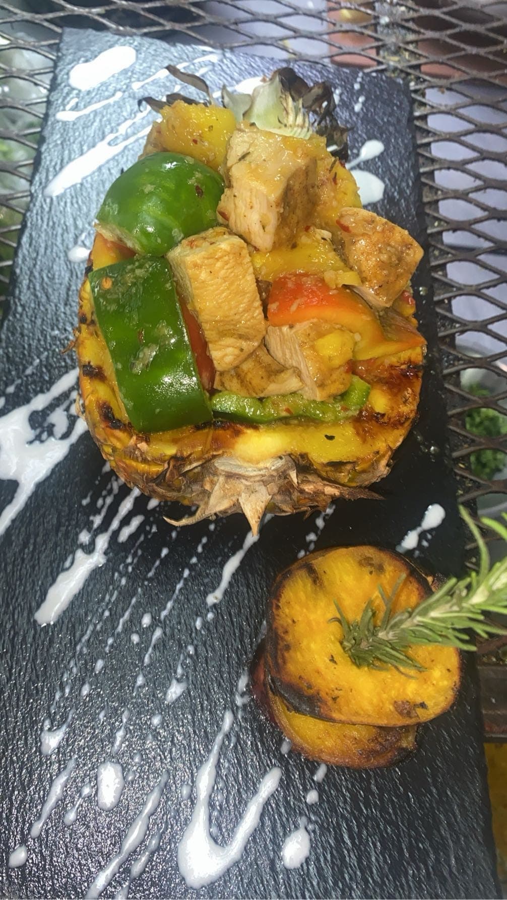 Pineapple boat filled with chicken and peppers, with a roasted side