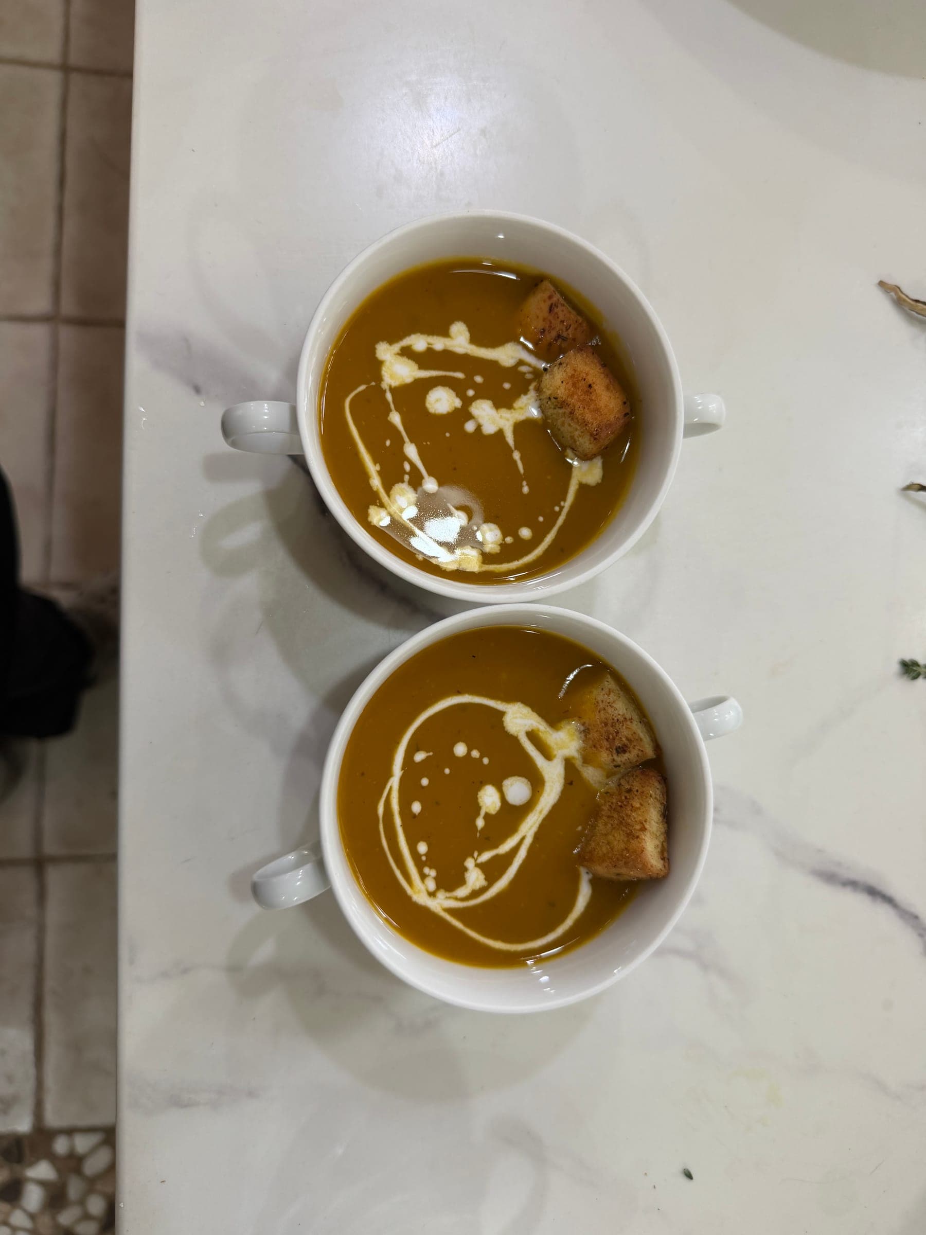 Two cups of soup finished with a cream swirl