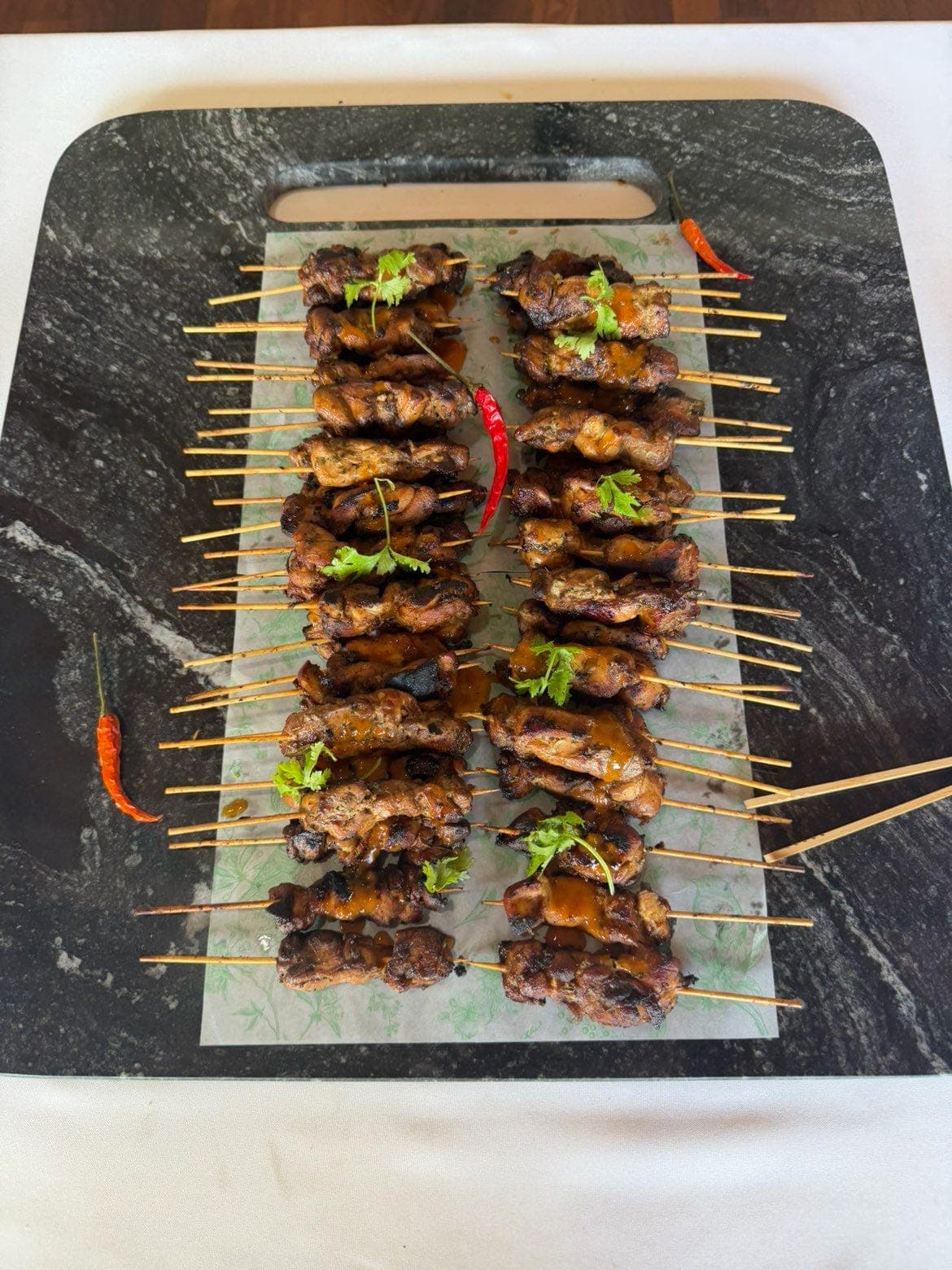 Rows of grilled skewers on a marble board