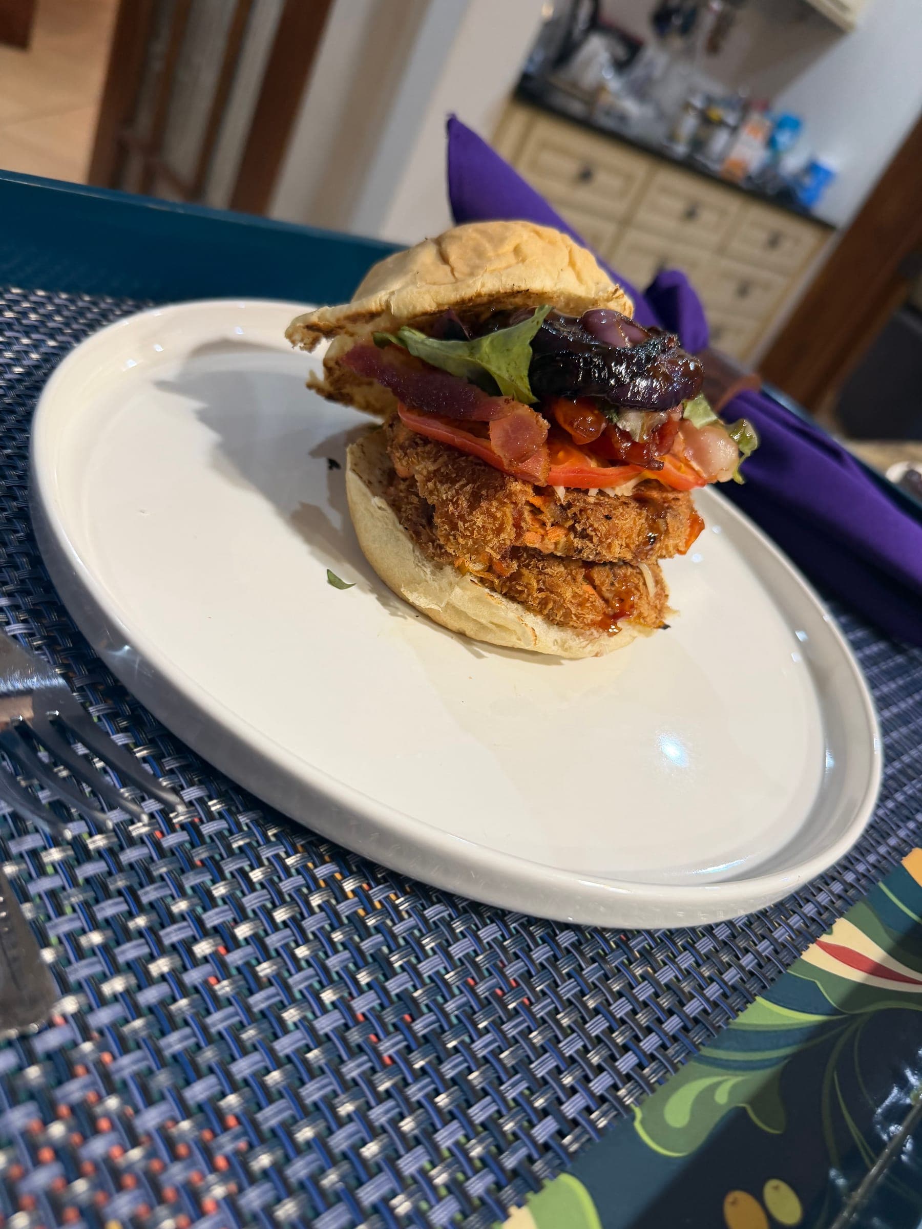 Stacked burger plated on a blue woven placemat