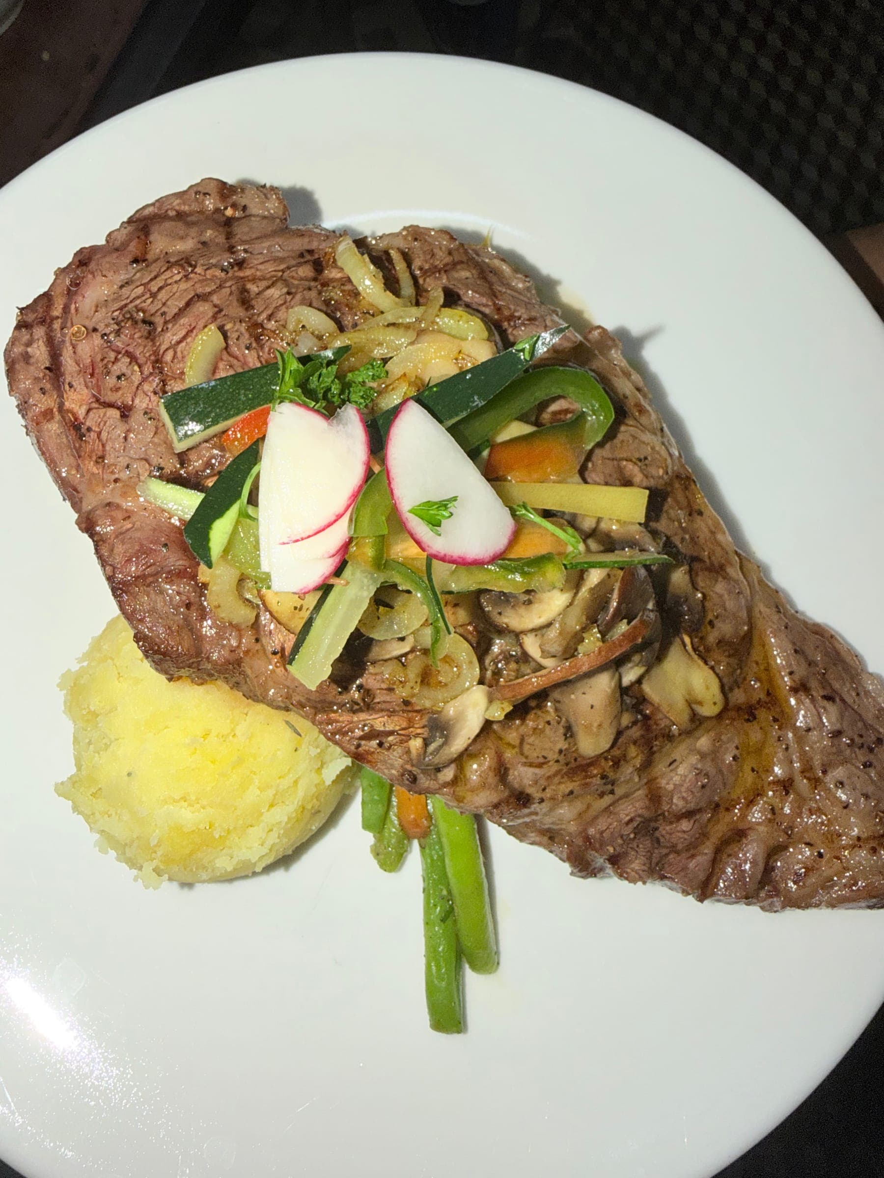 Grilled steak topped with fresh vegetables and herbs